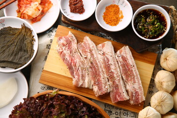 밑반찬과 생돼지고기가 있는 상차림 Table set with side dishes and raw pork