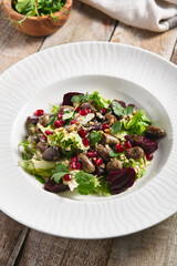 Warm Chicken Liver and Beet Salad. Restaurant food plate on wooden table. Vegetables, healthy, organic food concept