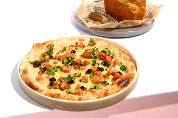 Olives and TOmato Focaccia and Cornbread on white table. White table and pink wall in sunlight with hard shadow. Summer day food concept.