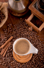 cup of coffee and coffee beans in a sack on dark background, top view
