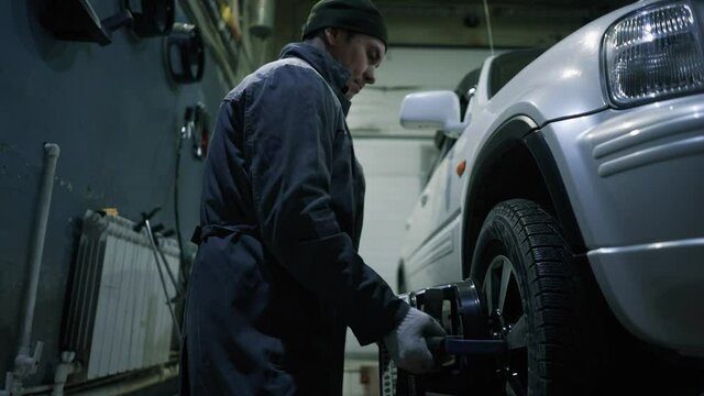 The car mechanic puts special sensors on the wheels to adjust the wheel camber.