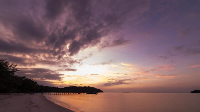 Sunrise timelapse on idyllic island beach with moving clouds and water reflection