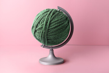 Globe made of knitting yarn on color background