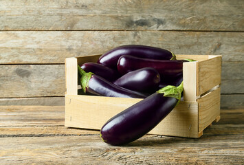 Box with fresh eggplants on wooden background