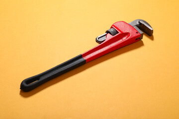 Plumbing wrench on color background