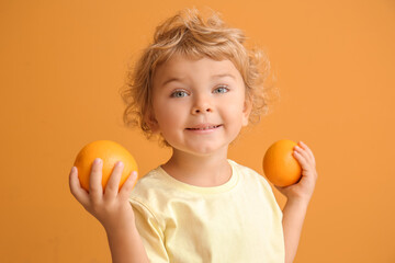 Cute little boy with oranges on color background