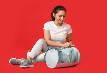 Obraz premium Young woman with sports bag on color background