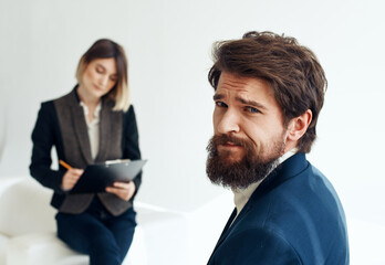 Business woman In a bright room and an upset man with a beard in the foreground is job interview