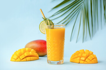 Glass of tasty mango smoothie on color background