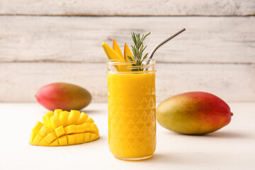 Fototapeta na wymiar Glass of tasty mango smoothie on light wooden background