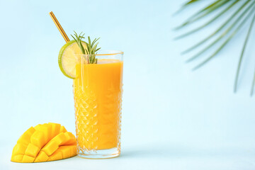Glass of tasty mango smoothie on color background