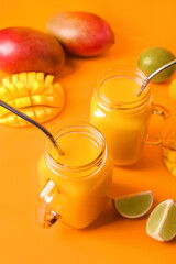 Mason jars of tasty mango smoothie on color background