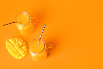 Mason jars of tasty mango smoothie on color background