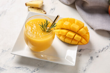 Glass of tasty mango smoothie on light background