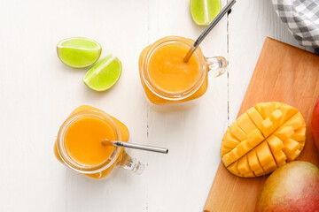 Mason jars of tasty mango smoothie on light background
