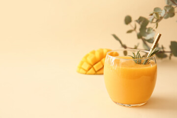 Glass of tasty mango smoothie on color background