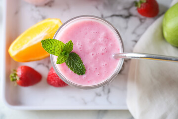 Glass of tasty fruit smoothie on light background