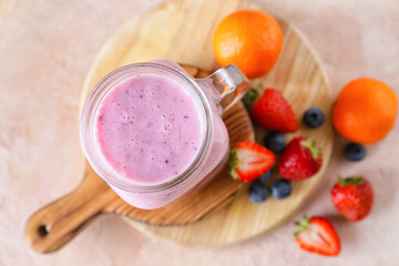 Mason jar of tasty berry smoothie on color background