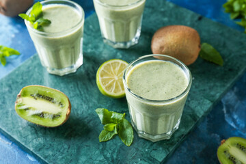 Glasses of tasty kiwi smoothie on color background