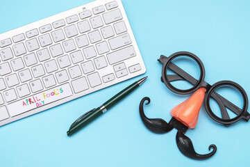 Computer keyboard and party decor for April Fools Day celebration on color background