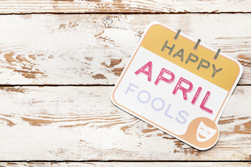 Paper sheet with text HAPPY APRIL FOOL'S on white wooden background
