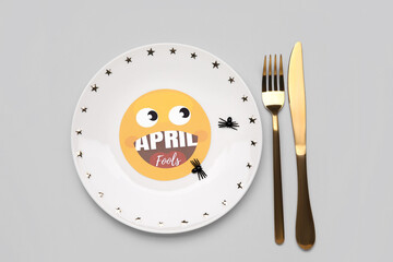 Plate with fake spiders and cutlery on grey background. April Fools Day celebration