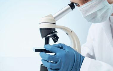 doctors in medical gloves look through a microscope on the table e laboratory chemical element...