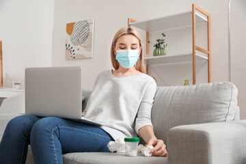 Sick young woman with laptop at home