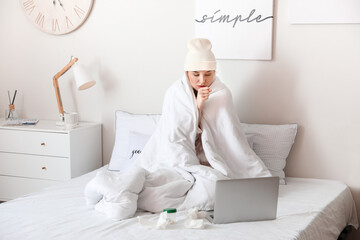 Sick young woman with laptop at home