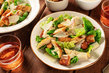 Caesar salad with a wine glass on a dark rustic wooden background