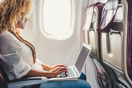 Modern young businesswoman work on flight travel airplane on board with wireless connection - people use technology laptop computer in travel - concept of remote workers and smart working free office