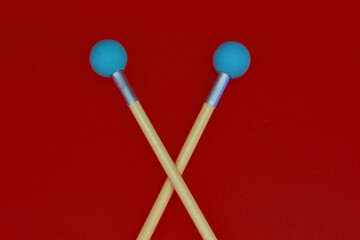 Detail of crossed xylophone
mallets on a red background.