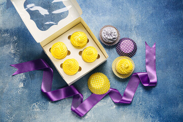 Box with tasty cupcakes on color background