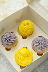 Box with tasty cupcakes on light background