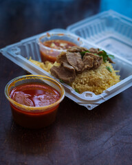 Roasted meat served with rice and chillies tamarind sauce and curry gravy in a take out container. Malaysian traditional cuisine, Nasi Daging Utara.