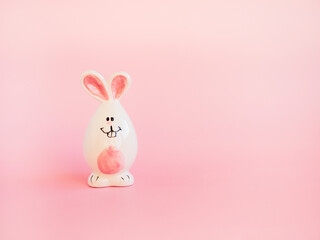 Cute white ceramic easter bunny or rabbit on pink background. Minimal Holiday concept. Symbol Happy Easter holiday. Creative. Copy space