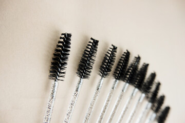 lot of the same new brushes for eyebrows on a beige background, selective focus