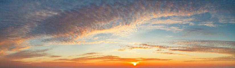 panoramic view from an airplane on a beautiful saturated sunrise above the clouds in red and orange shades