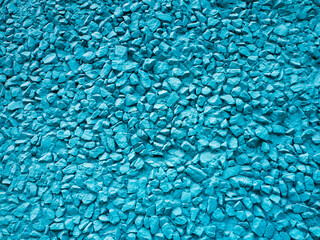 The wall of the building is decorated with fine gravel and painted blue. Abstract background with plaster and pebbles.