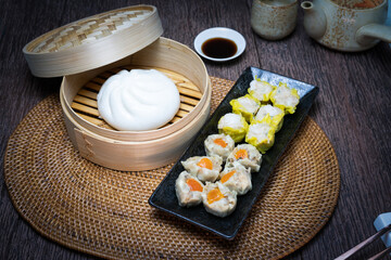 Chinese steamed meat bun and Steamed dumplings with sauce on  wooden background are ready to serve and eat.