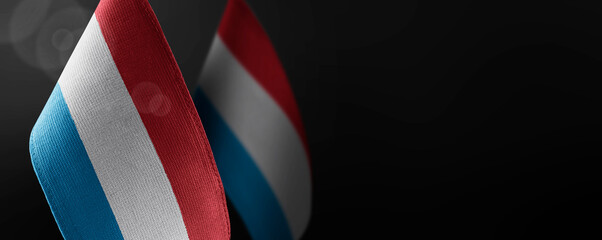 Small national flags of the Luxembourg on a dark background