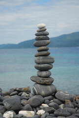 Fototapeta premium Pebbles are piled on a volcanic rock by the sea. Zen concept. Copy space.