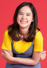 Asian girl Wear yellow shirt and short skirt pose in advertising and presenting goods and contents gesture with friendly smile face on red background.