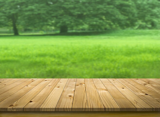 Perspective brown wooden board mock up display as empty shelf or desk with blurred green natural background.