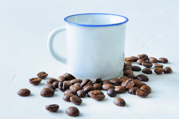 White mug and roasted coffee beans on a light background