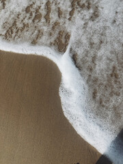 Sea small wave on the sandy shore of the Baltic Sea view from above, macro. vertically