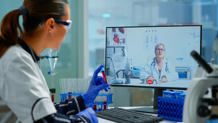 Physician doctor offering medical online advices to chemist student using pc. Scientist holding blood sample during online discussion, virtual conference, helping on telemedicine, healthcare support