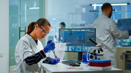 Scientist in modern equipped medical laboratory examinining drug discovery with micropipette....