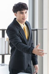 Asian businessman in a suit extends his right hand to check. To make an agreement with person In the concept of doing business Inside a white room