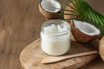 Obraz na płótnie Canvas Jar of coconut butter and fresh coconuts with palm leaf on wooden background.